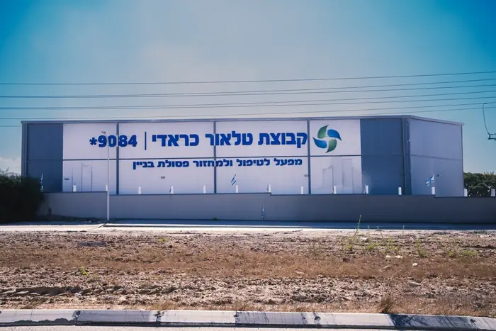 מבנה מפעל לטיפול ומחזור פסולת בניין של הקבוצה, עם השלט *9084